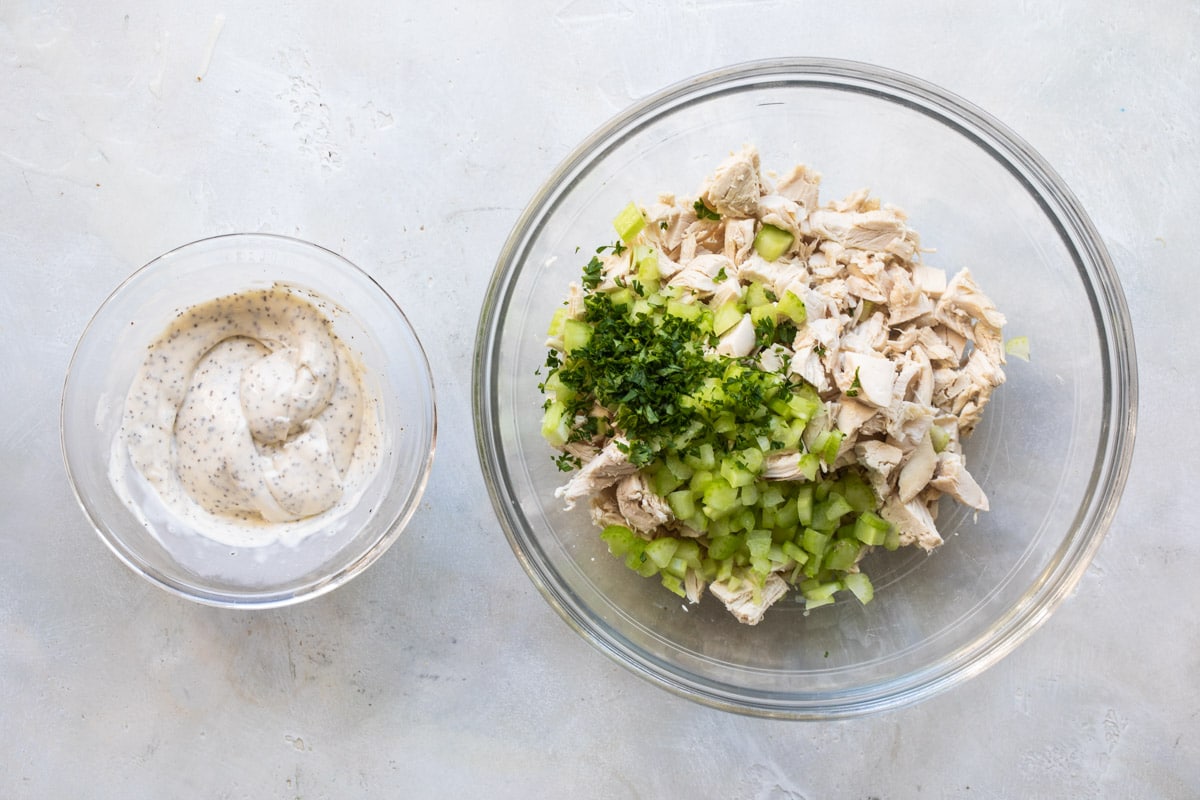 Chicken salad sauce next to a bowl of chicken salad ingredients.