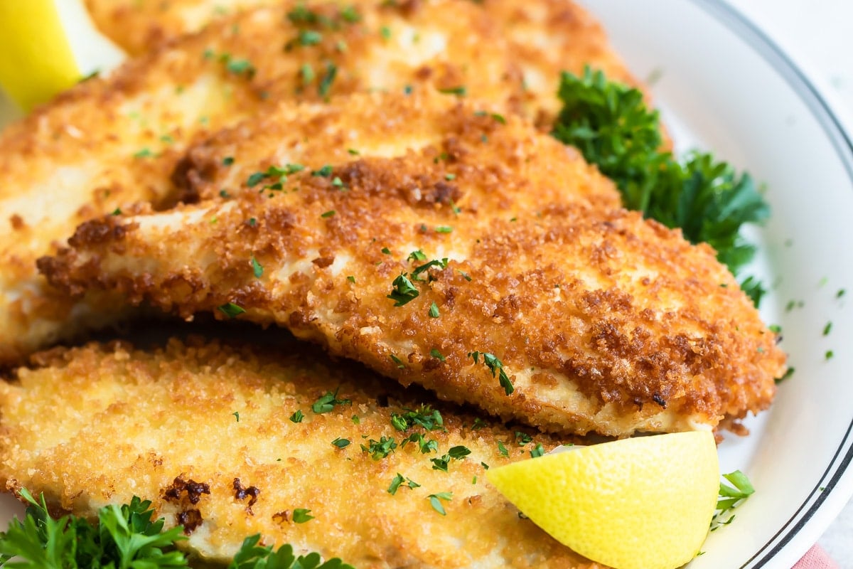 Chicken Schnitzel garnished with a lemon and parsley.