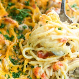 Chicken spaghetti being scooped out of a green casserole dish.
