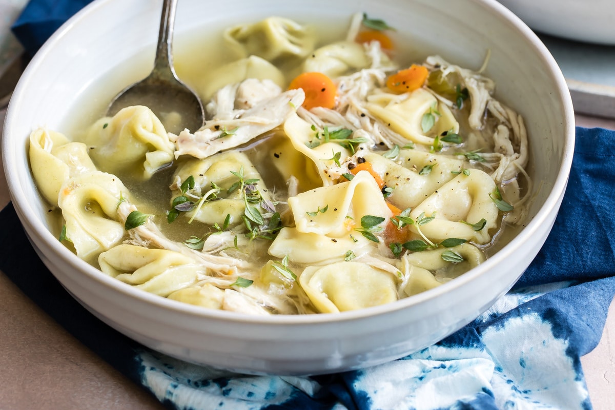 Slow cooker chicken tortellini soup in a white bowl.