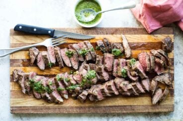 Chimichurri steak on a wooden cutting board.