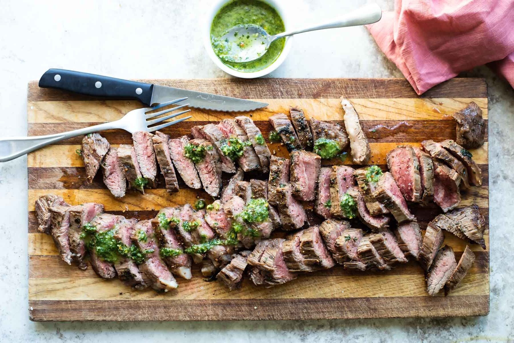 Chimichurri steak on a wooden cutting board.