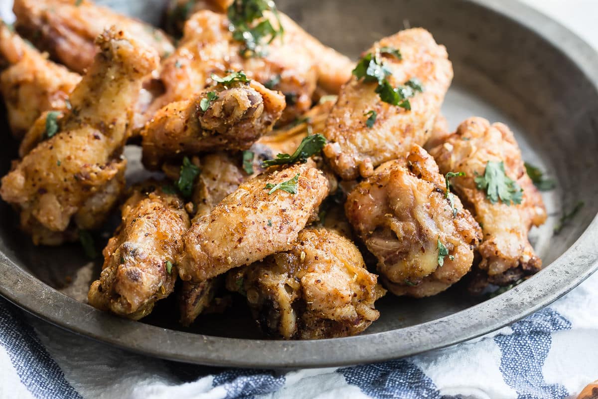A bowl of Chinese chicken wings next to some pints of beer.
