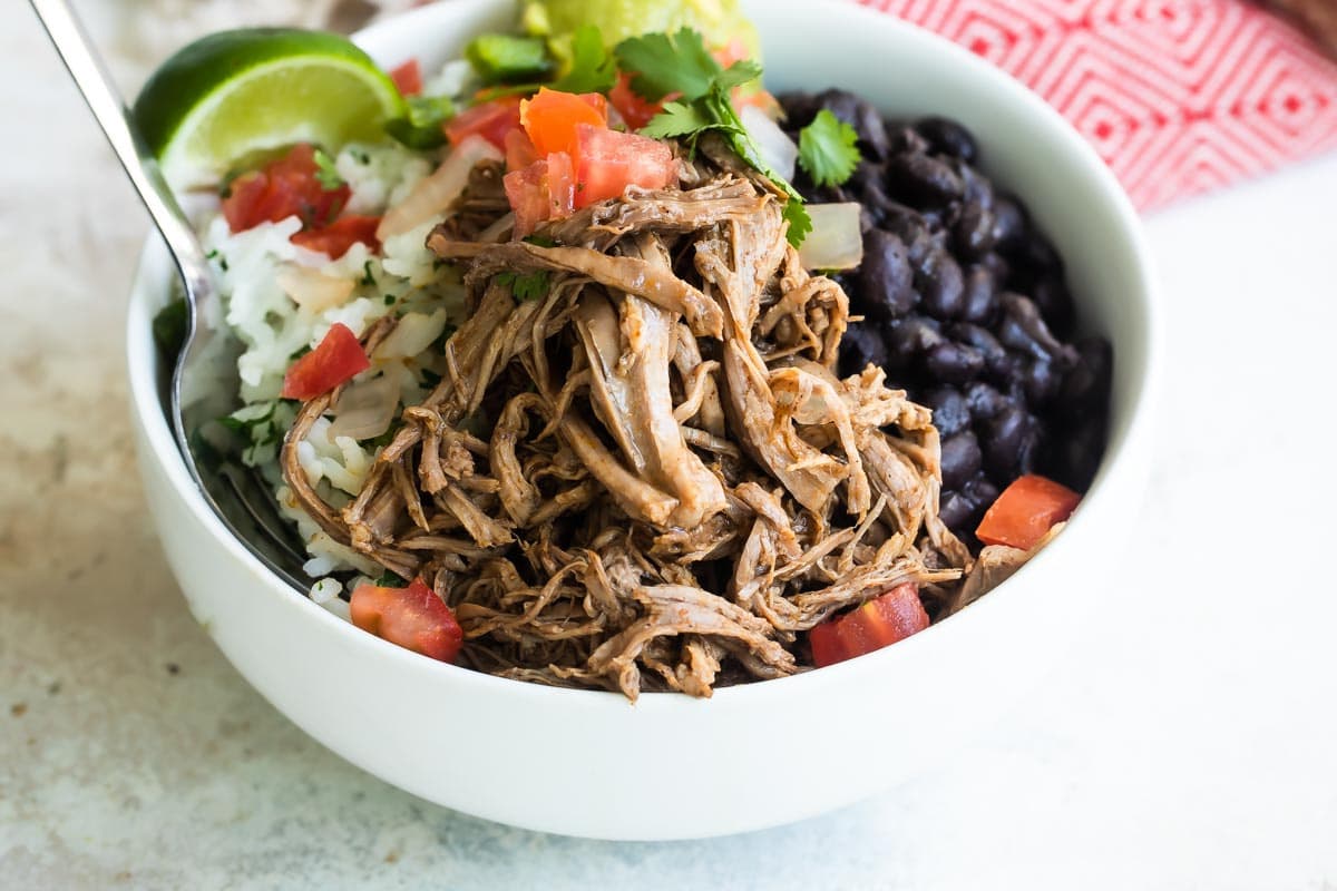 A bowl of Chipotle copycat Barbacoa beef with black beans, cilantro-lime rice, and pico de gallo salsa.