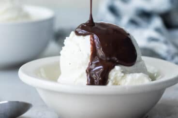 Chocolate sauce being drizzled on a scoop of vanilla ice cream.