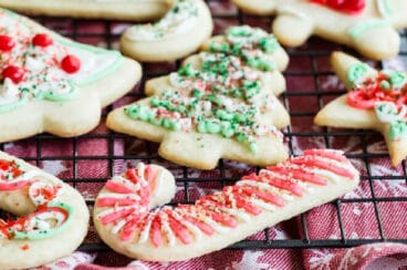 Frosted sugar cookies decorated for Christmas on a baking rack.