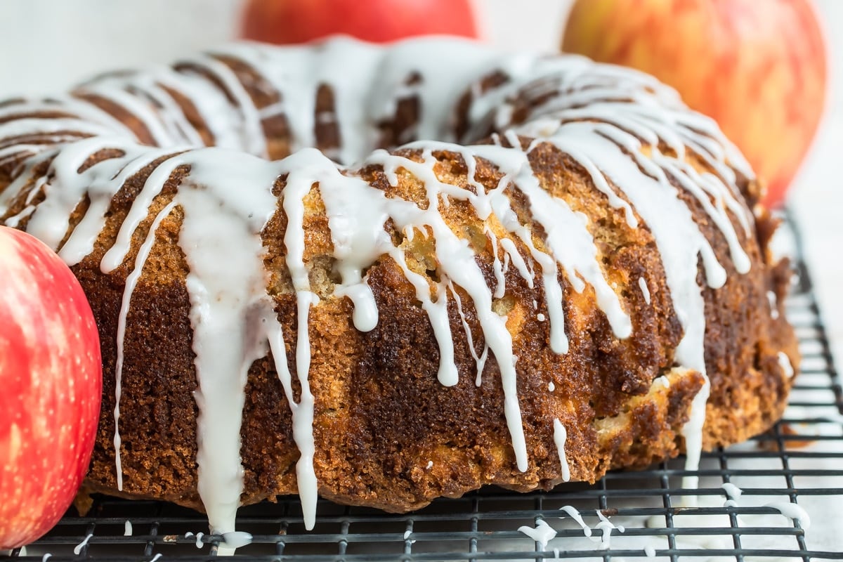 Cinnamon Apple Cake on a cooling rack surrounded by apples.