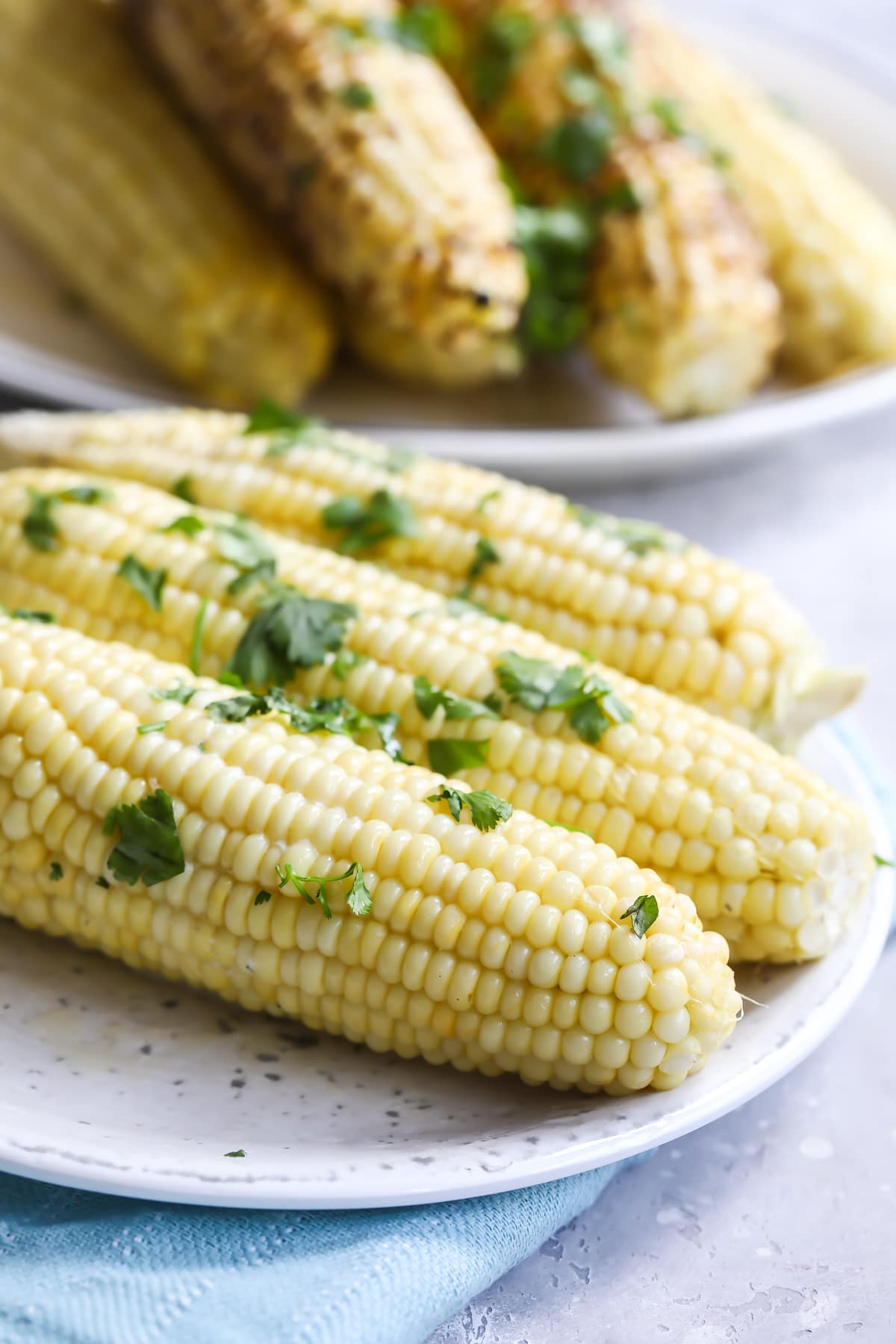 4 ears of corn on a white plate.
