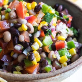 Cowboy caviar in a bowl on a white plate with tortilla chips.