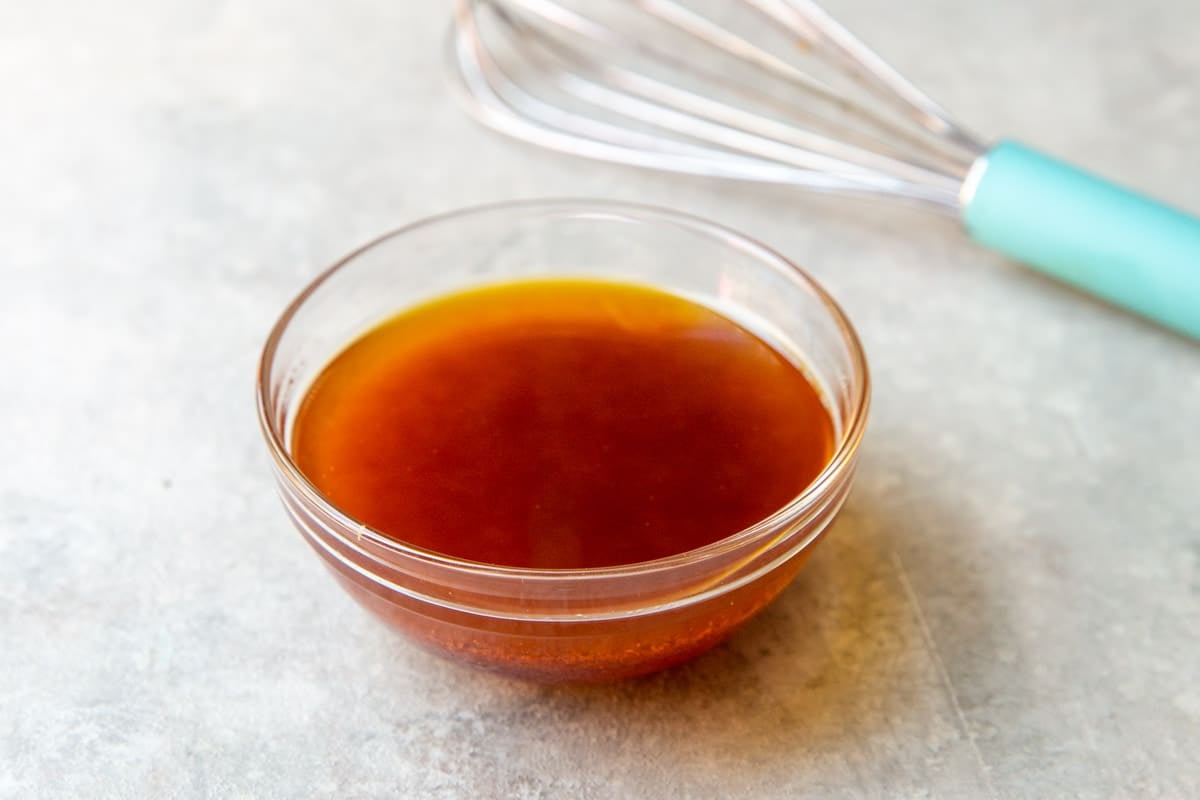 Cowboy Caviar salad dressing in a clear glass bowl with a whisk in the background.