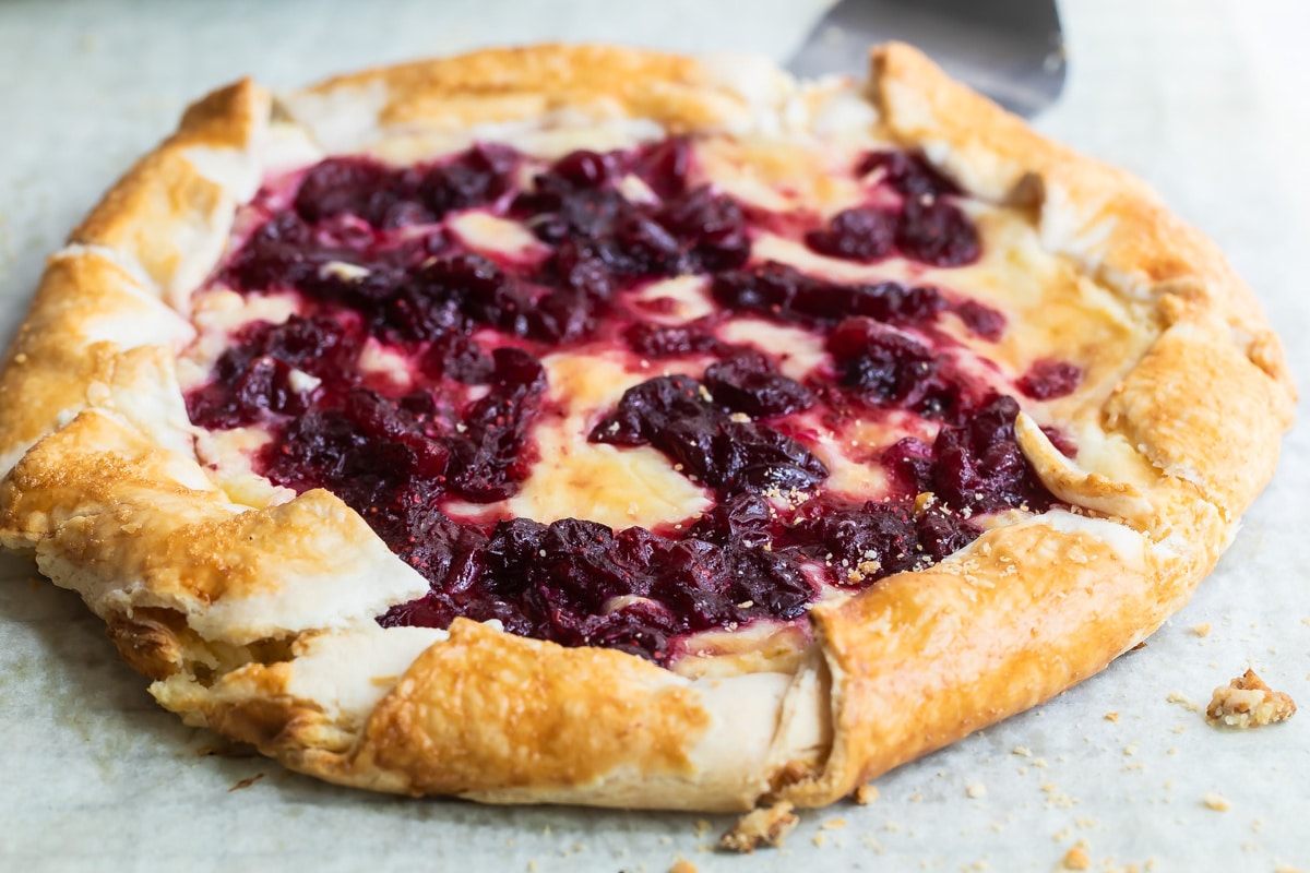 Cranberry cheesecake galette on a piece of parchment paper over a cooling rack.