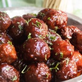 A metal pie pan filled with crockpot meatballs.