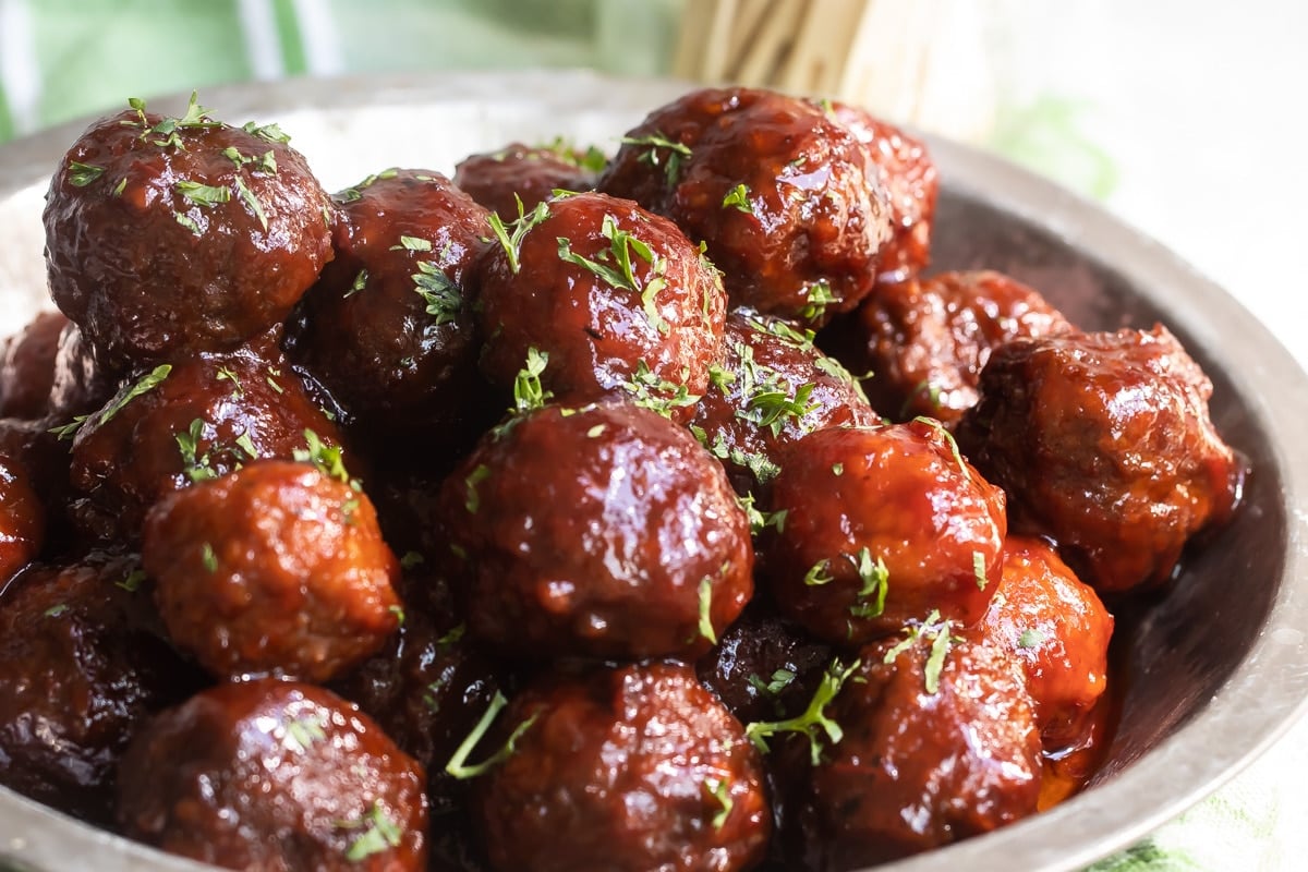 A metal pie pan filled with crockpot meatballs.