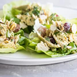 A white plate with lettuce cups filled with curried chicken salad.