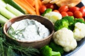 A platter with dill dip and fresh vegetables.