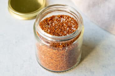 A small glass jar full of dry rub seasoning.