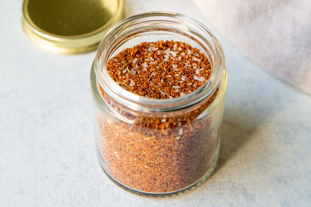 A small glass jar full of dry rub seasoning.