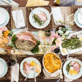 A table set for Easter with baked ham, scalloped potatoes, roasted green beans, and homemade biscuits.