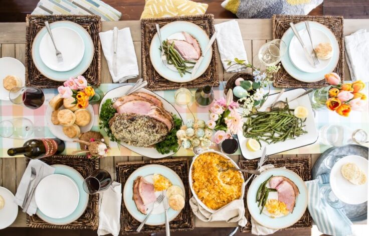 A table set for Easter with baked ham, scalloped potatoes, roasted green beans, and homemade biscuits.