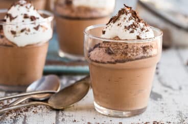 Small cups of chocolate mousse next to spoons.
