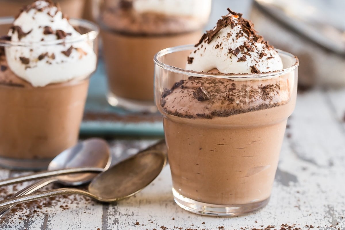 Small cups of chocolate mousse next to spoons.