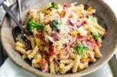Easy cold pasta salad in a wooden bowl with a serving fork and spoon.