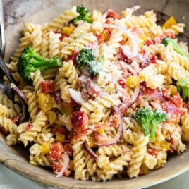 Easy cold pasta salad in a wooden bowl with a serving fork and spoon.
