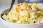 A white s erving bowl with potato salad.