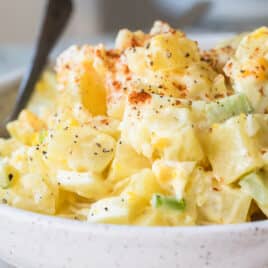A white s erving bowl with potato salad.