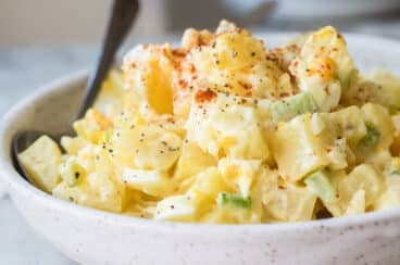 A white s erving bowl with potato salad.