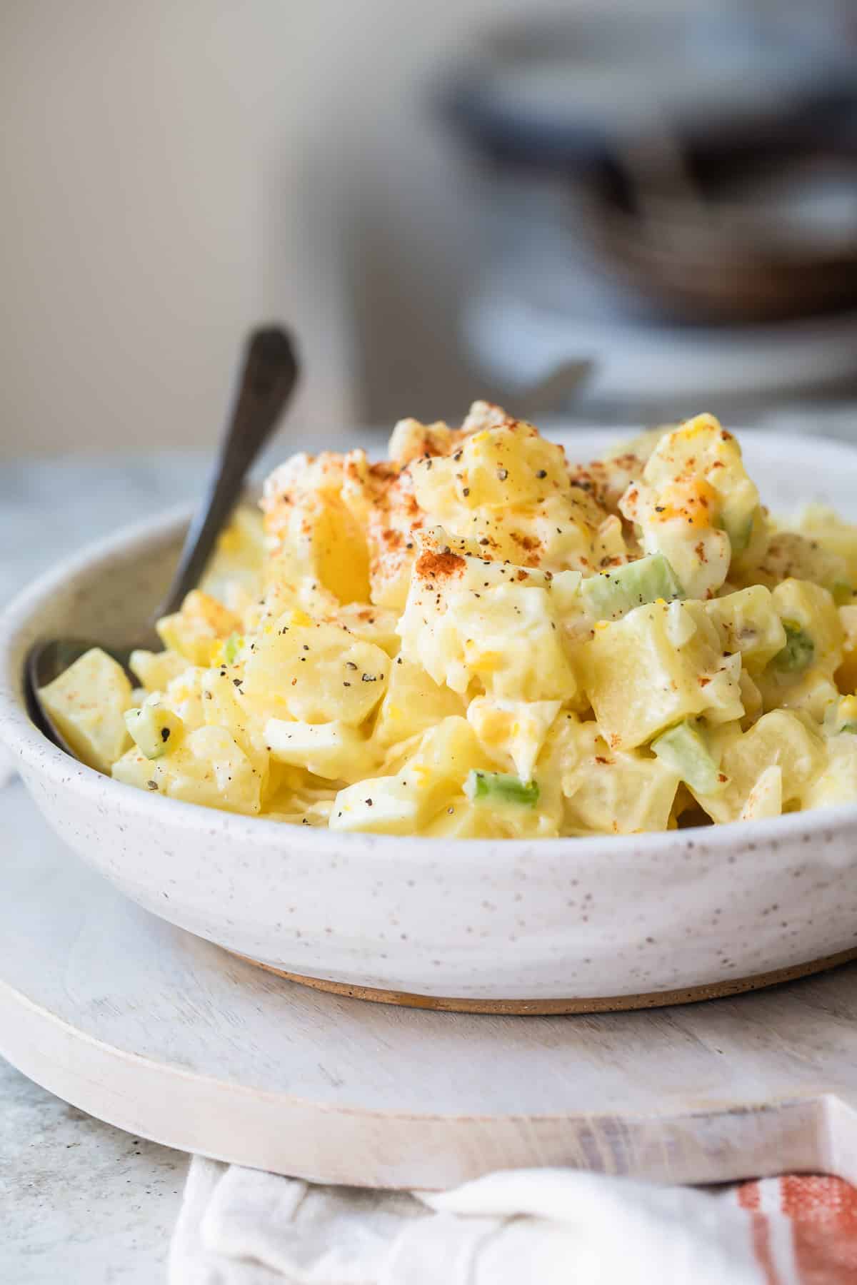 A white s erving bowl with potato salad.