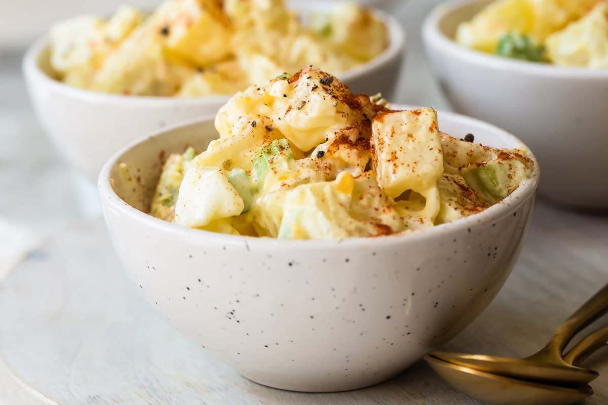 A white s erving bowl with potato salad.