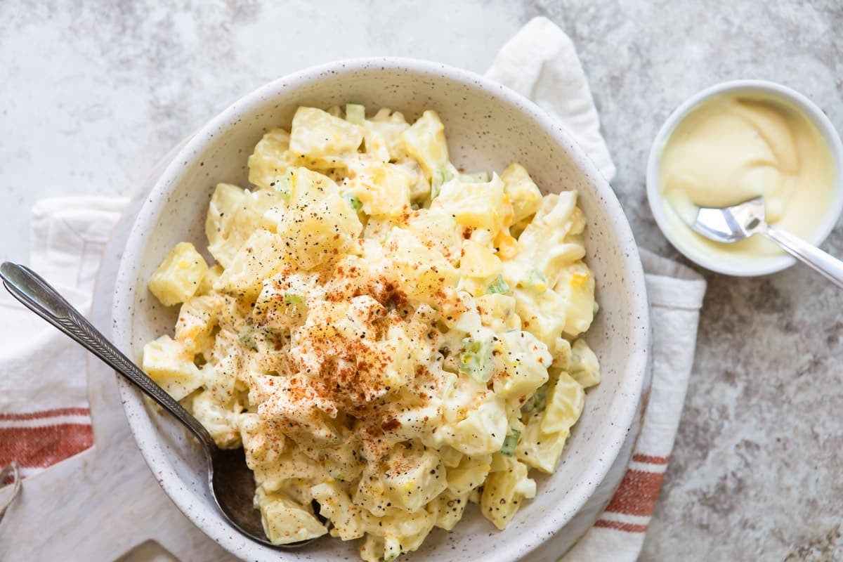 A white s erving bowl with potato salad.