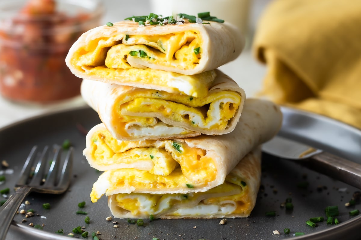 Egg burritos stacked on a gray plate.