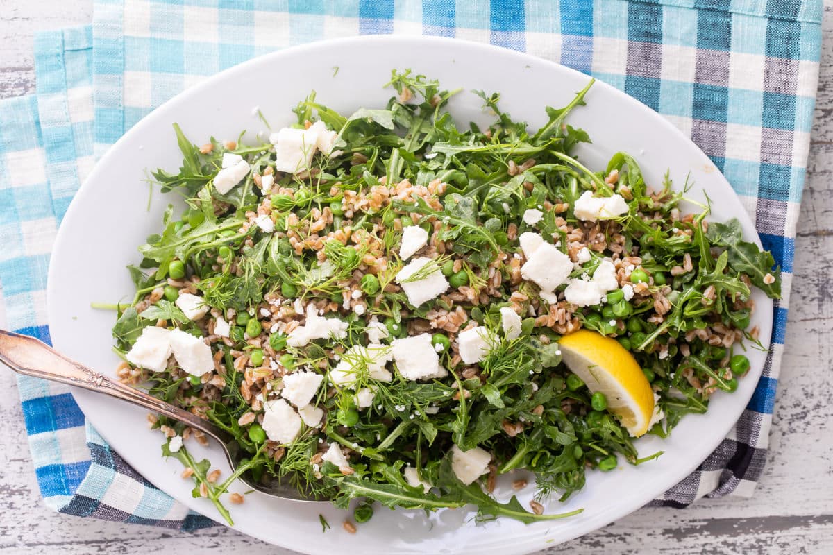 Farro salad with peas and feta on a white plate.