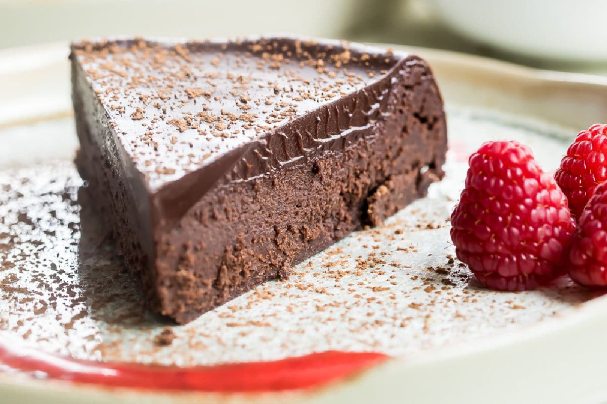 Flourless chocolate cake slice on a white plate.