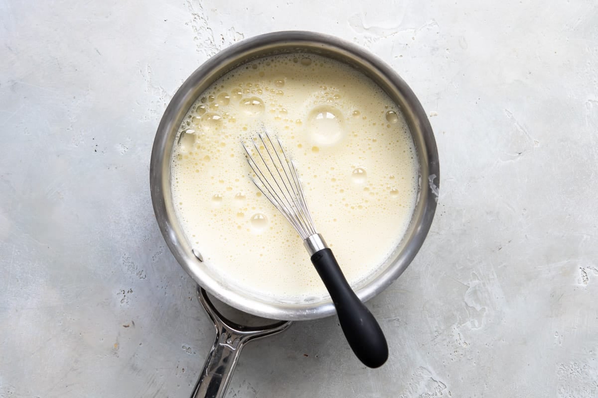 Stirring hot milk into pastry cream.
