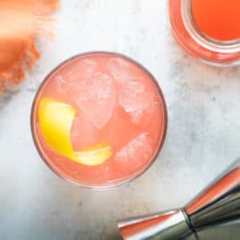 A Greyhound cocktail next to a carafe of grapefruit juice.