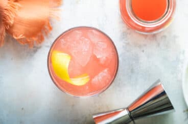 A Greyhound cocktail next to a carafe of grapefruit juice.