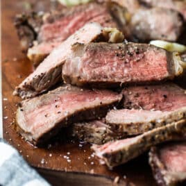 Grilled New York strip slices on a wooden cutting board.