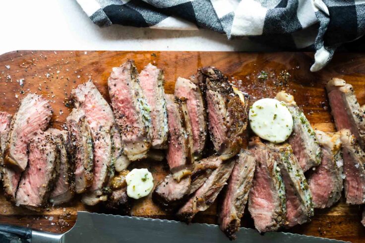 Sliced New York strip steaks on a cutting board.