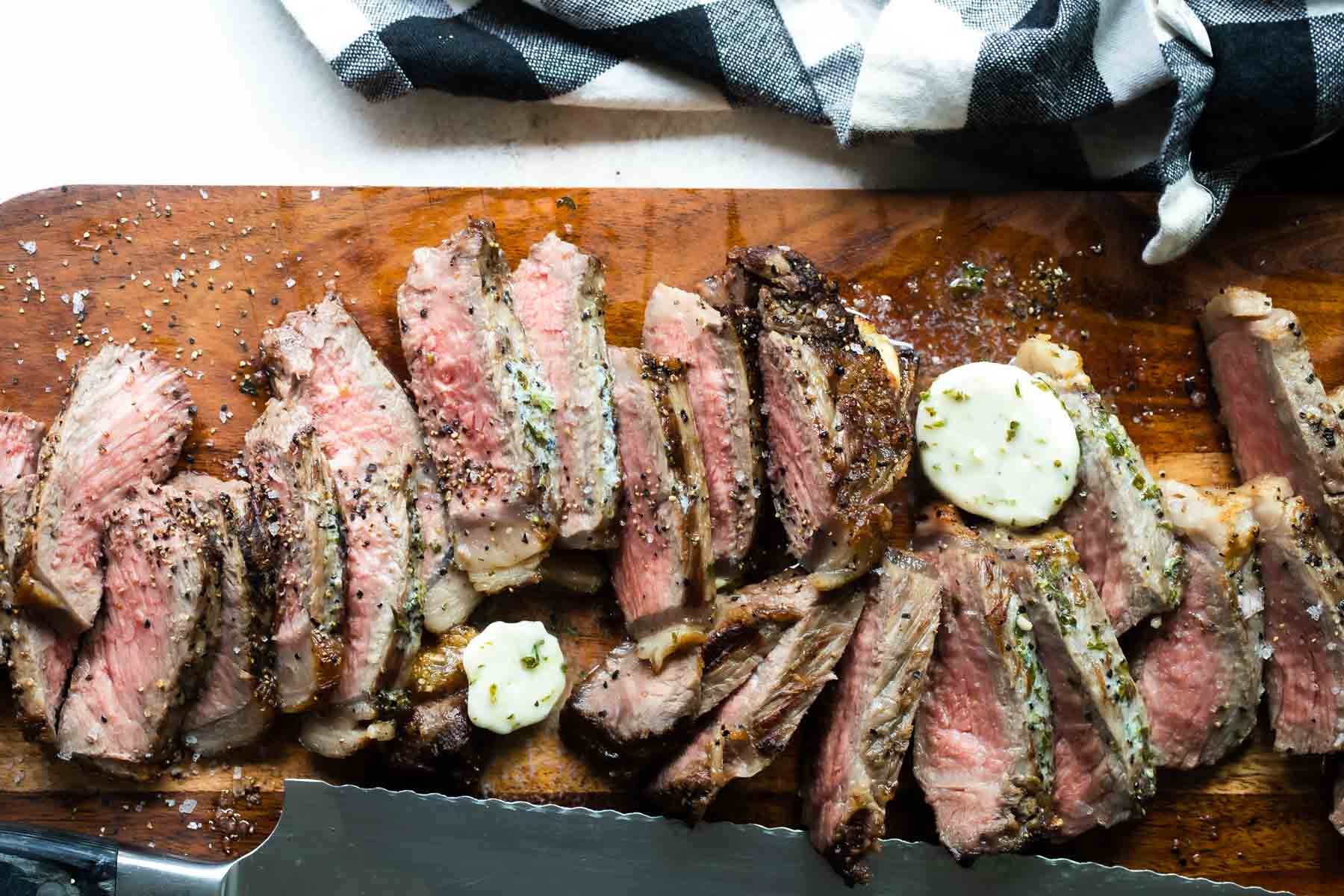 Sliced New York strip steaks on a cutting board.