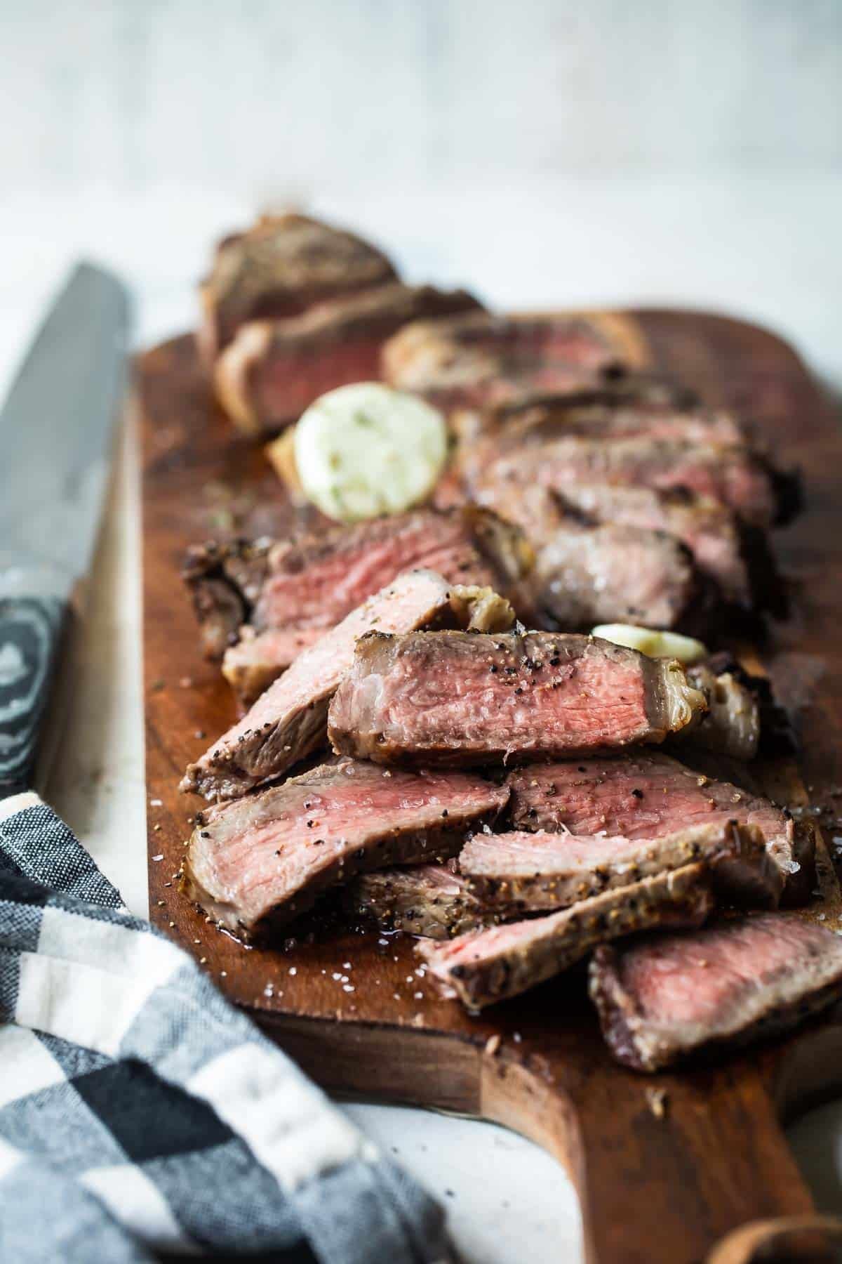 Sliced New York strip steaks on a cutting board.
