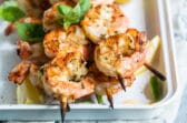 Grilled shrimp skewers in a white tray.