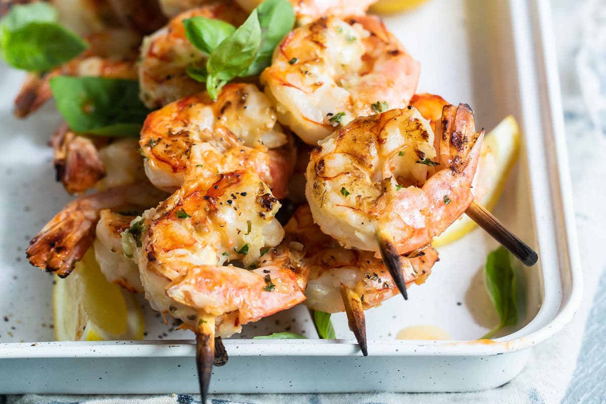 Grilled shrimp skewers in a white tray.