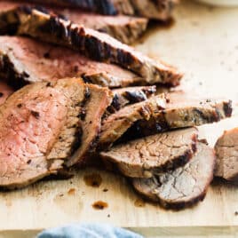 A cutting board with a sliced tri tip on top.