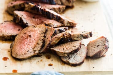 A cutting board with a sliced tri tip on top.
