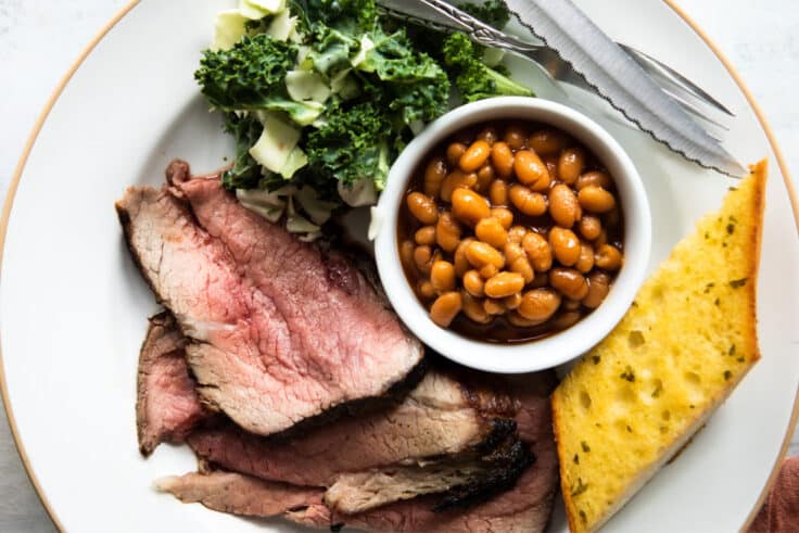 A plate of Santa Maria barbecue with tri-tip, salad, beans, and garlic toast.