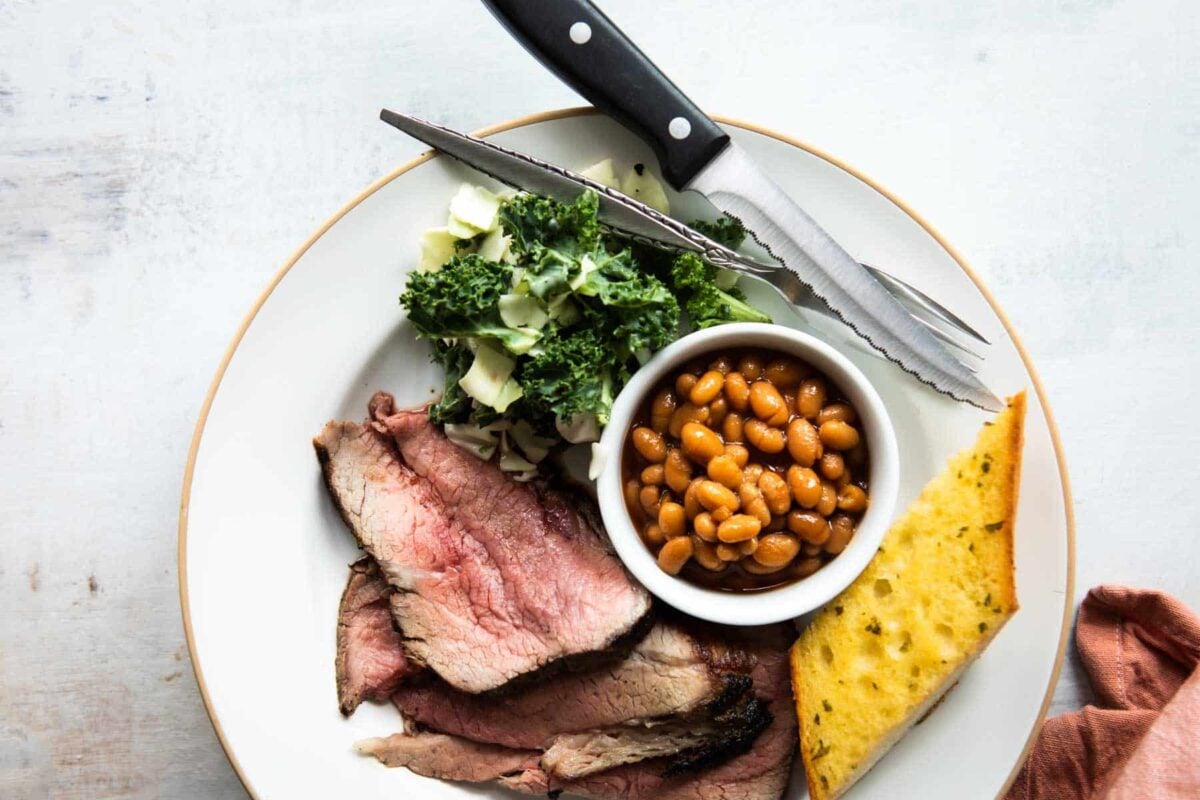 A plate of Santa Maria barbecue with tri-tip, salad, beans, and garlic toast.