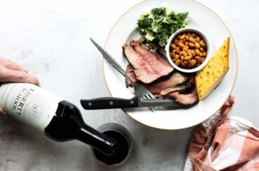 A plate of Santa Maria barbecue with tri-tip, salad, beans, and garlic toast.